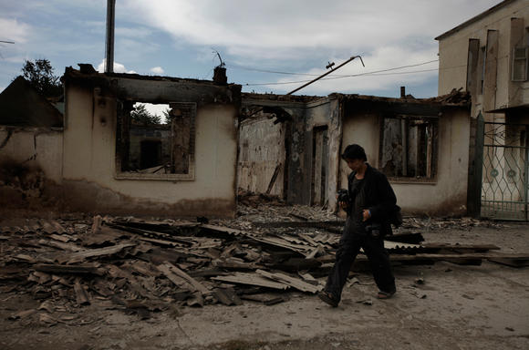 Ed Ou photographs a burned home after ethnic Kyrgyz mobs rampaged through minority Uzbek enclaves, burning homes and businesses in Shark, Kyrgyzstan. (Photo by Marina Gorobevskaya)