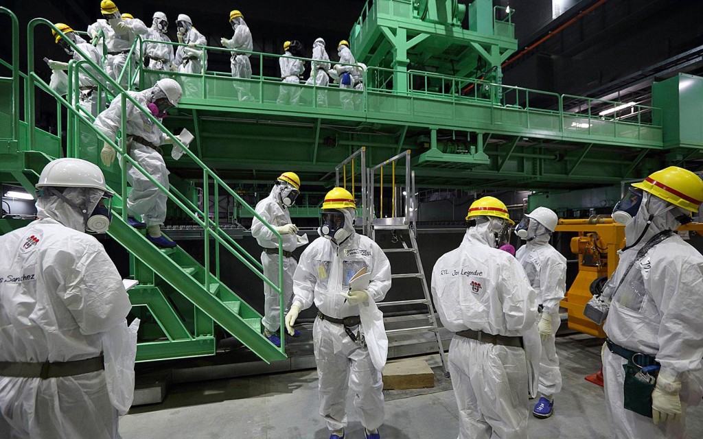 Members of the media and TEPCO employees walk down the steps of a fuel handling machine on the spent fuel pool inside the No.4 reactor building in Fukushima