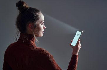 Female scans face using facial recognition system on smartphone for biometric identification. Future high tech technology and face id