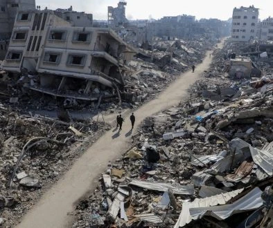 Palestinians walk past destroyed houses, in Jabalia refugee camp