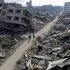 Palestinians walk past destroyed houses, in Jabalia refugee camp