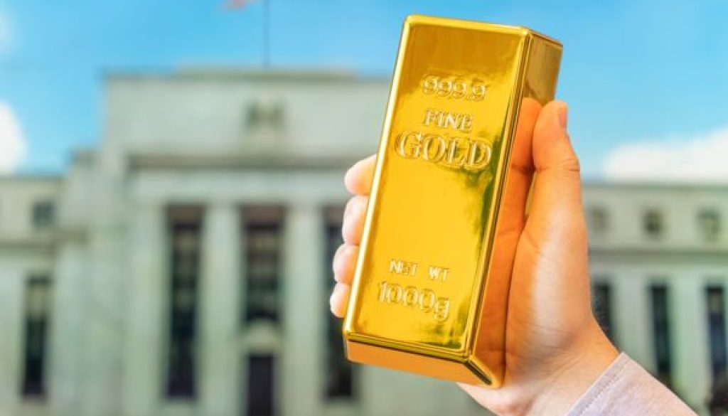 A,Gold,Bar,In,A,Man's,Hand,Against,The,Background