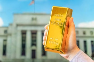 A,Gold,Bar,In,A,Man's,Hand,Against,The,Background