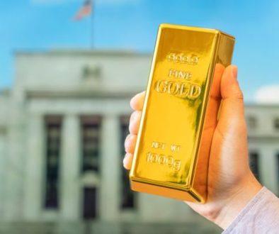 A,Gold,Bar,In,A,Man's,Hand,Against,The,Background