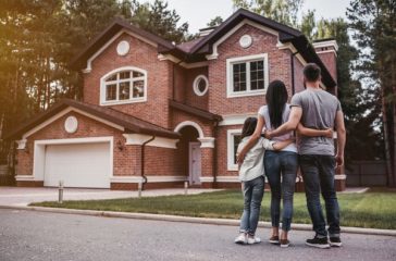 Back,View,Of,Happy,Family,Is,Standing,Near,Their,Modern