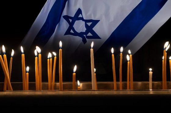 Burning candles with Israeli flag. Composition with a flag of Israel for Memory day, memorial of heroes and victims of war in Middle East.