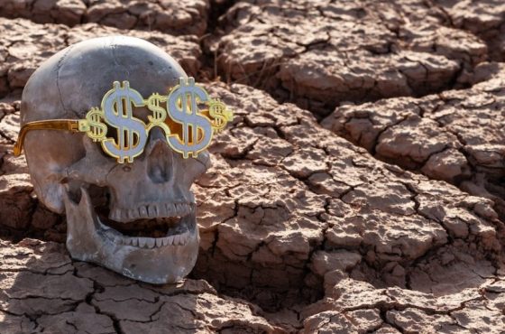 Skull of a man wearing glasses with an image of the US dollar symbol on heat-cracked clay in the desert