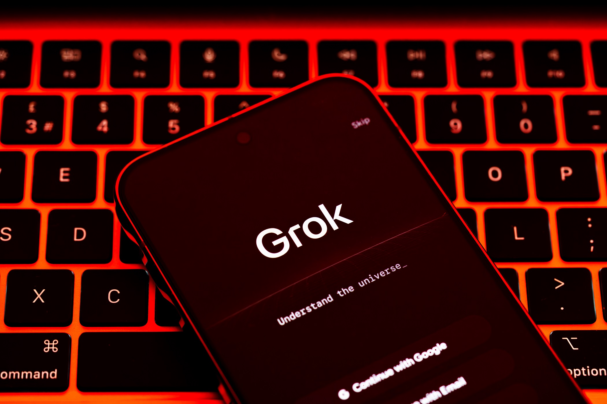 Grok AI app screen on smartphone placed on illuminated red keyboard, wide composition for artificial intelligence and online safety news coverage. Stafford, United Kingdom, January 7, 2026,