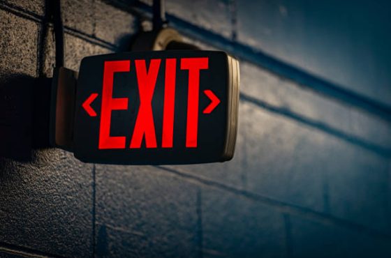 glowing exit sign by night on black wall