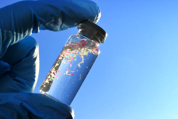 A glass vial containing water and micro plastic pieces of pollution A glass vial containing water and micro plastic pieces of pollution