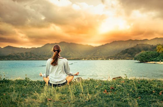 Woman meditating at sunset, mindfulness, inner peace.